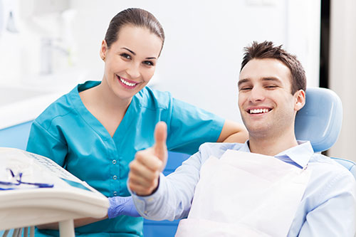 smiling man at dental office giving a thumbs up